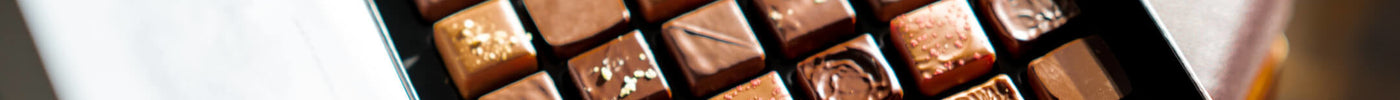 A box of thirty six chocolate squares sits on a table in the center of the image
