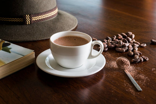 cup of hot chocolate next to cacao beans